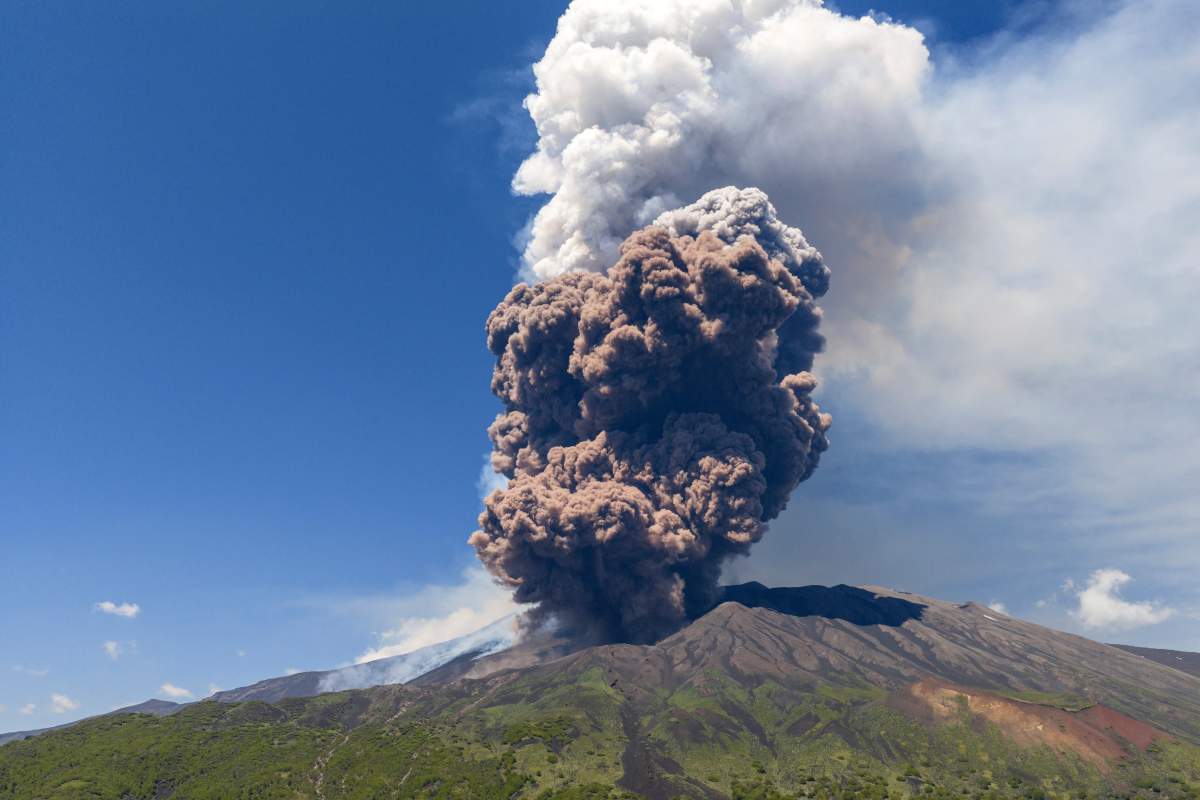 Photo-realistic aerial view of Mount Etna volcano, Sicily, Italy, showing the smoking summit craters and Valle del Bove, clear blue sky, high resolution scientific photography