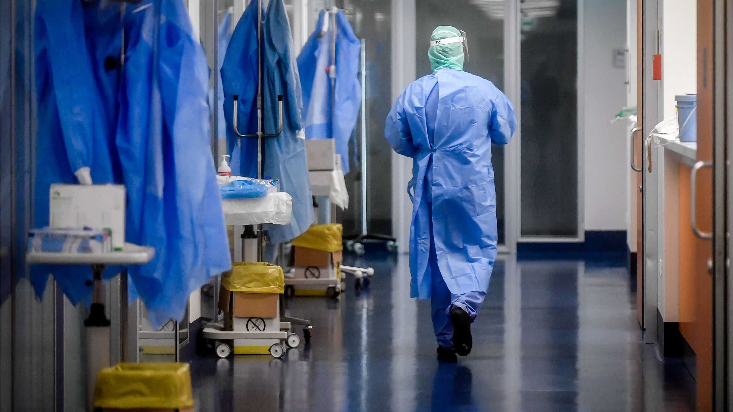 Doctors and nurses in full PPE gear working in a busy hospital hallway during pandemic, realistic style