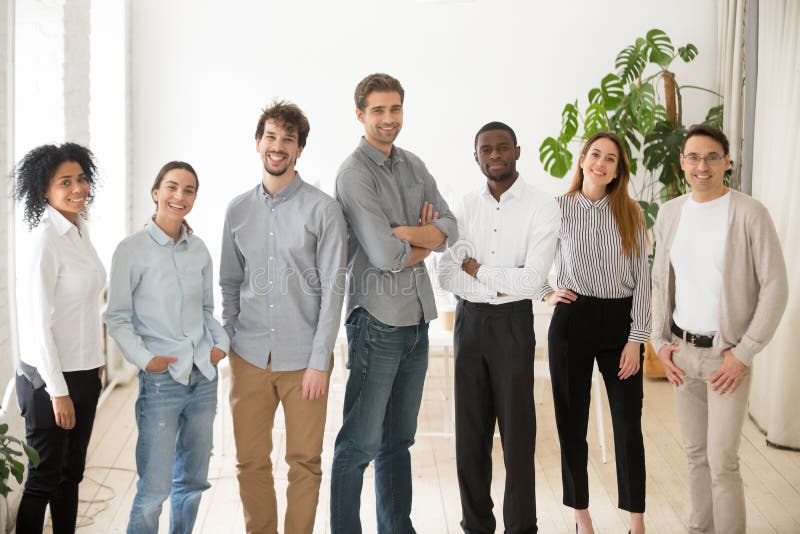 diverse group of young adult professionals smiling and standing confidently in an office lobby
