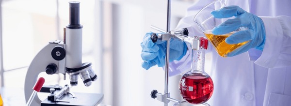 Science class lab equipment: beaker with white glue, pipette, safety goggles on table. Photorealistic.