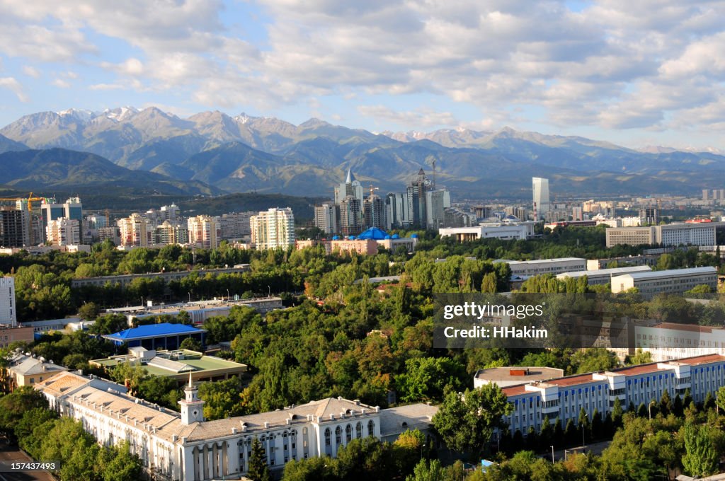 Skyline of Almaty Kazakhstan with modern buildings and mountains in the background, daytime, realistic photography style