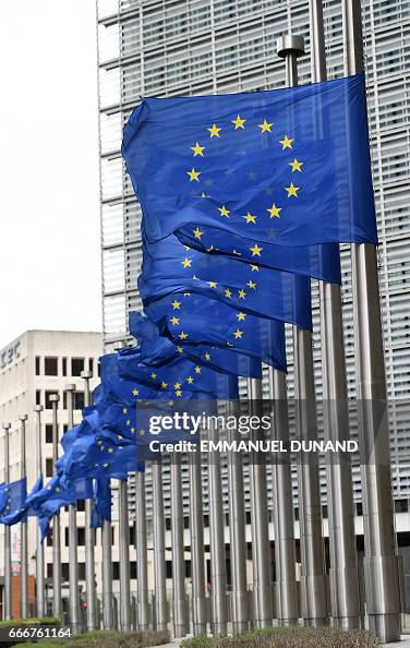 European Union flags waving in front of the Berlaymont building in Brussels, cinematic lighting, professional photography, high resolution
