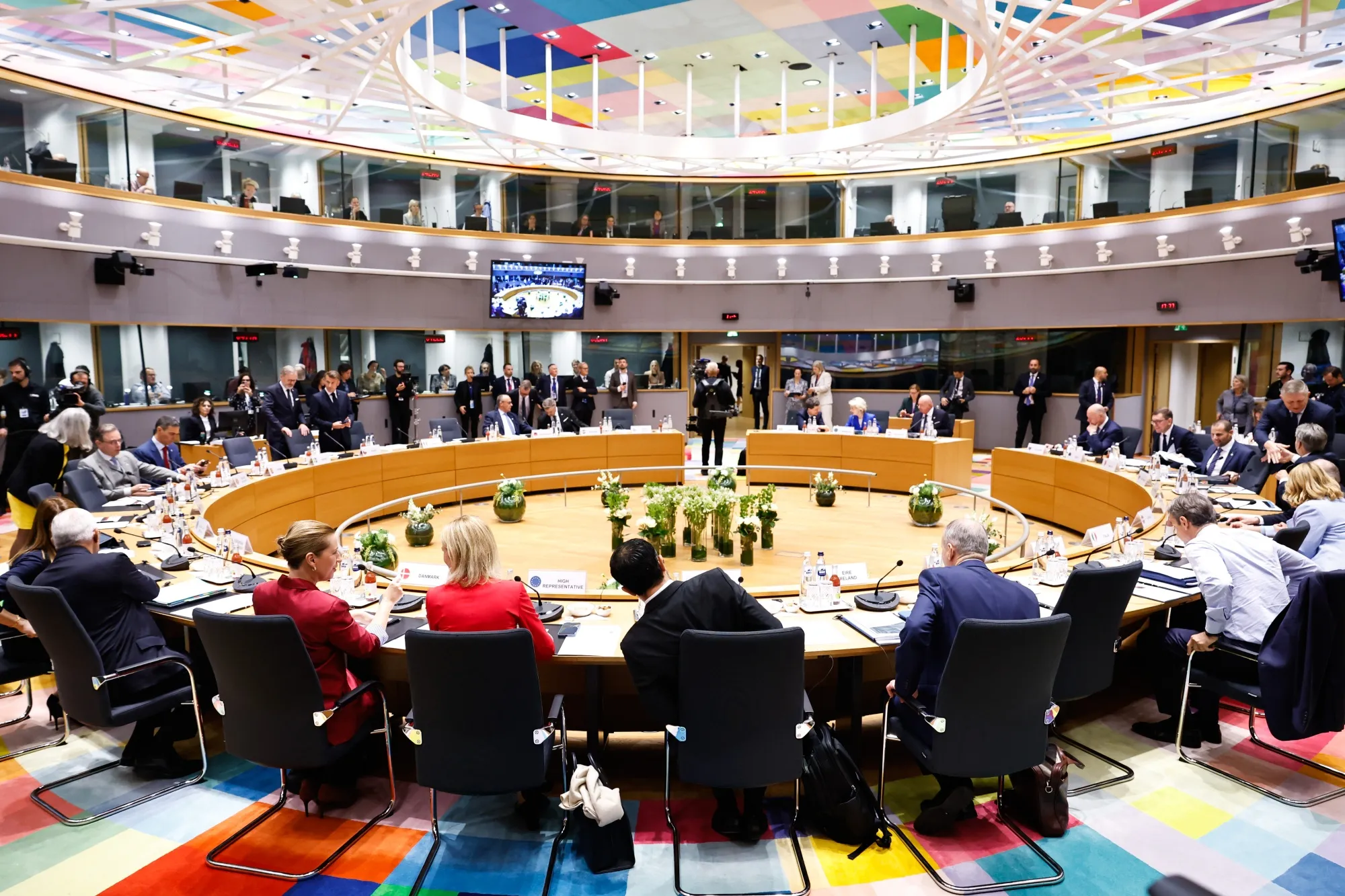 Meeting of the Council of the European Union, foreign ministers sitting at round table, flags of member states visible