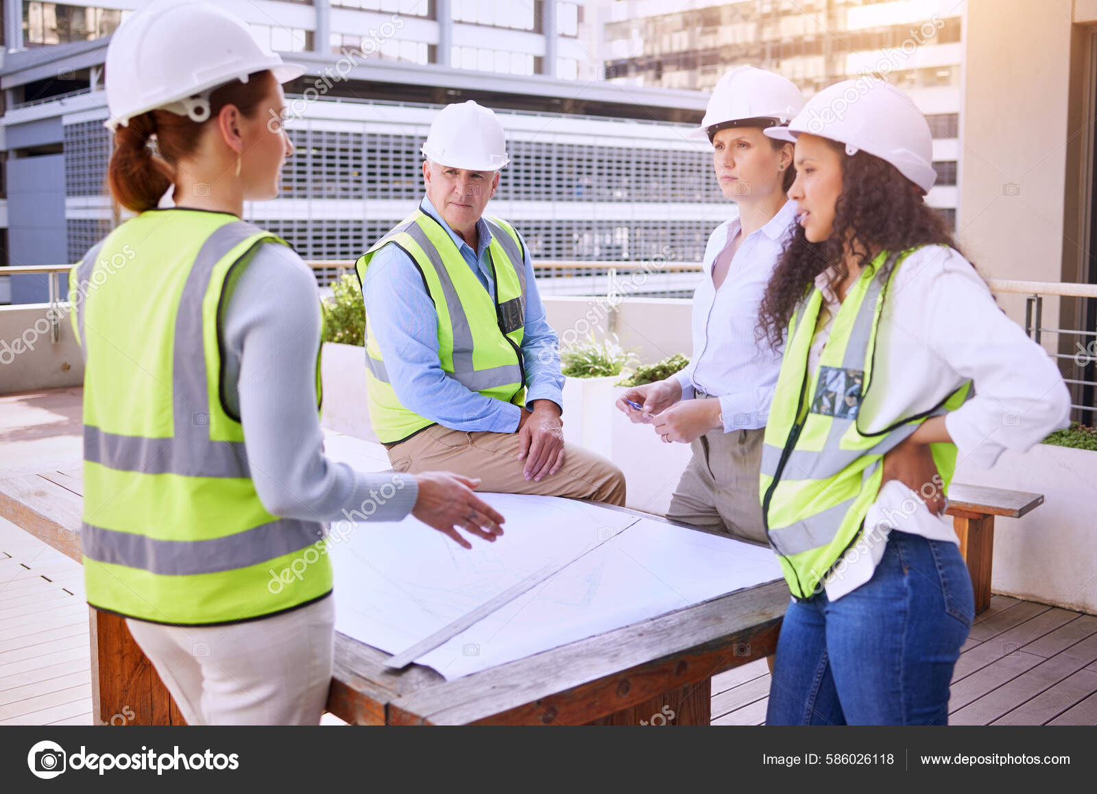 Construction workers looking at blueprints on site, team of builders, realistic