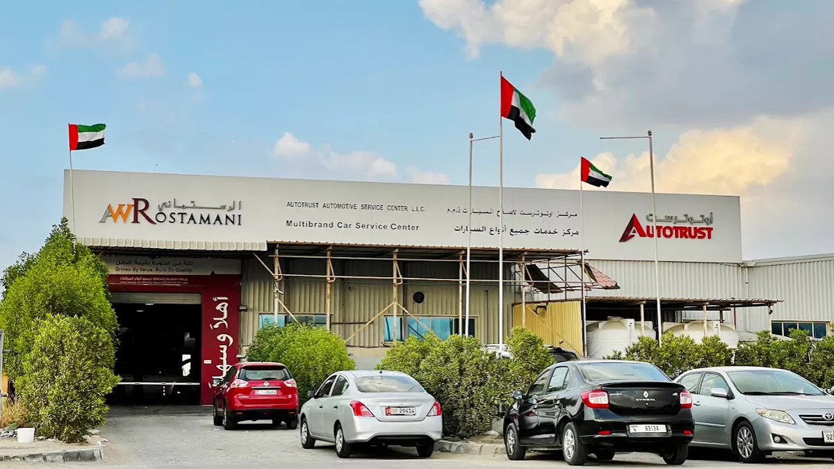 Autotrust Dubai service center building exterior, modern automotive workshop, sunny day, professional branding