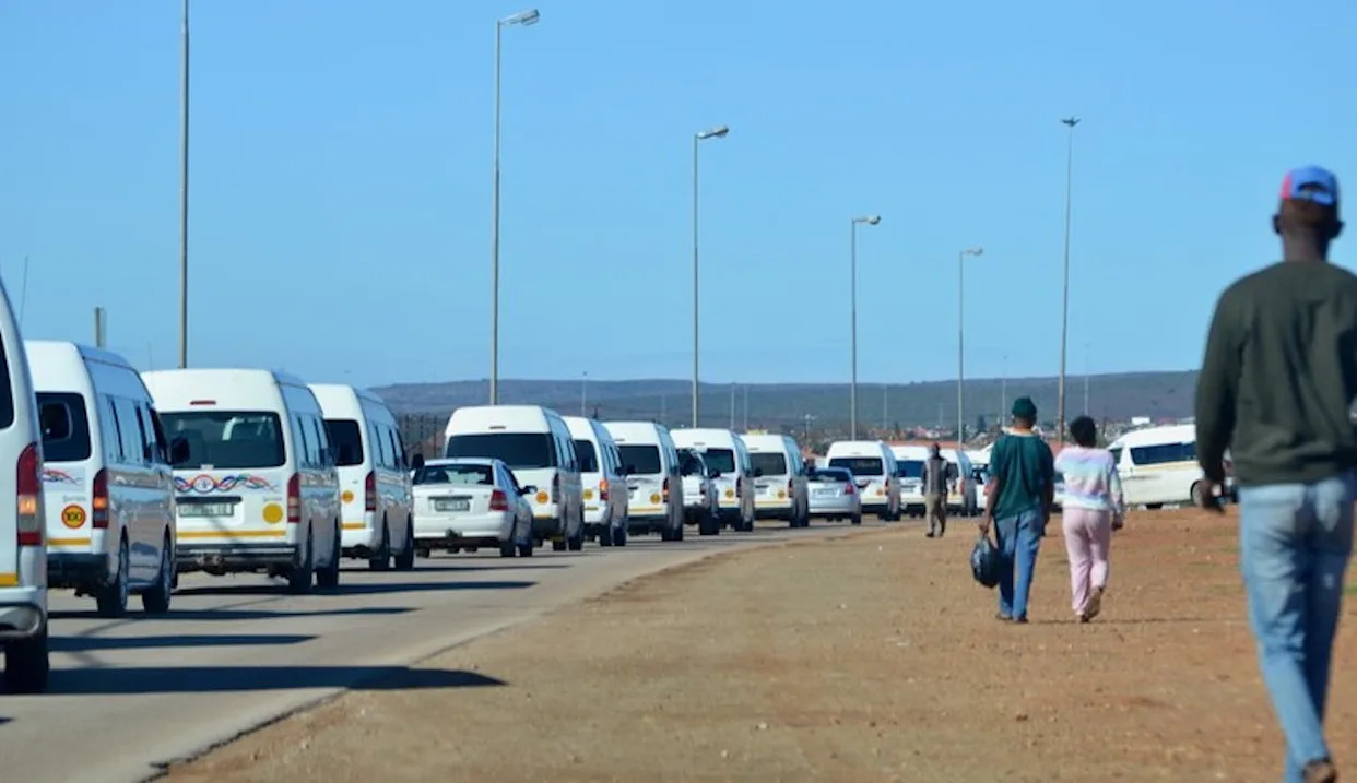 South African taxi rank busy scene, white minivan taxis, outdoors, transportation hub